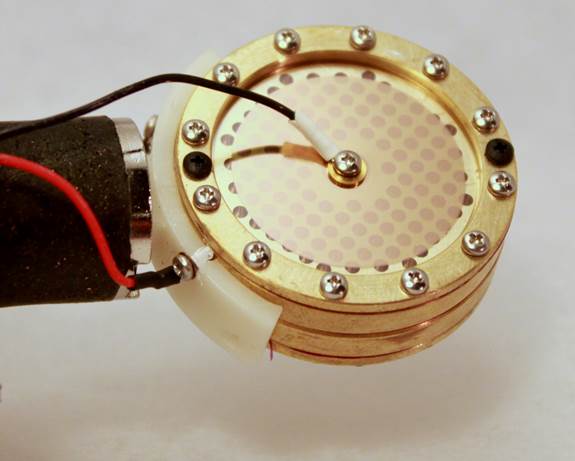 K87-style brass capsule in its saddle with four thin wires soldered to the diaphragm and backplate terminals.
